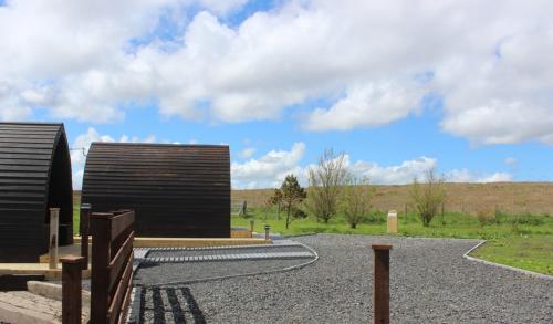 a couple of black buildings in a field at Hillside Camping Pods and Shepherd's Hut in Wick