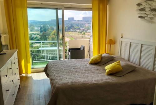 a bedroom with a bed and a large window at Résidence meublée STUDIOTEL in Cagnes-sur-Mer