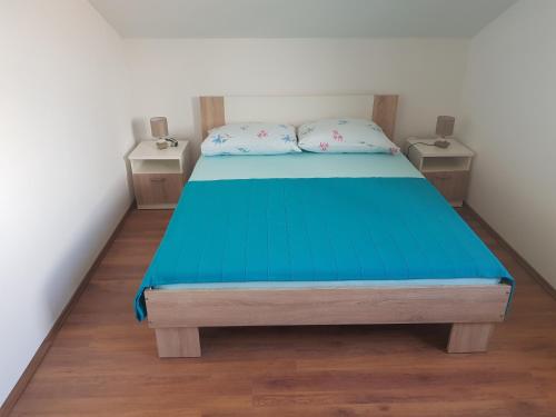 a bedroom with a blue bed with two night stands at Apartman Ravlić in Malinska