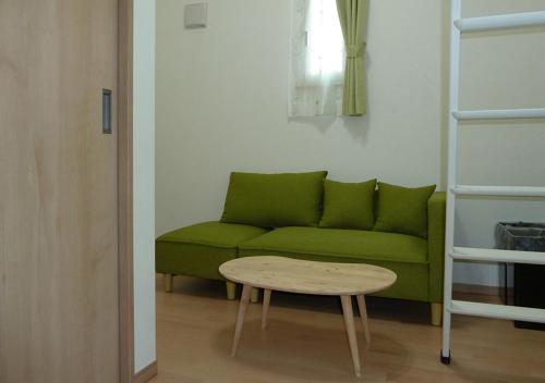 a living room with a green couch and a table at Kanaloa Funabashi in Funabashi