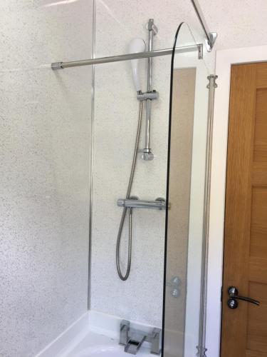 a shower with a glass door next to a sink at Lochalsh View, Kyle, 1 Mile to Skye in Kyle of Lochalsh