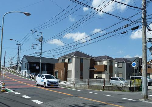 a white car driving down a road with buildings at Kanaloa Funabashi in Funabashi