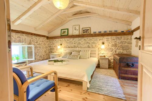 a bedroom with a large bed and a stone wall at White Cottage Heritage House in Čižići