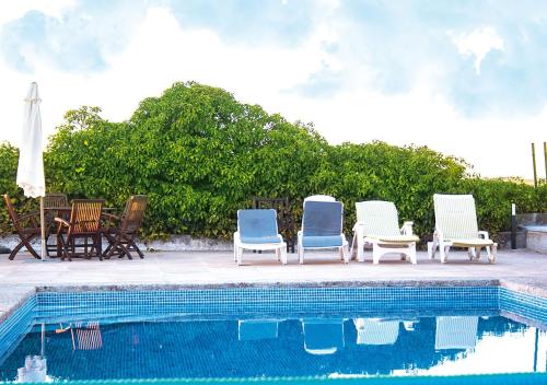 - un groupe de chaises assises à côté de la piscine dans l'établissement Casa Rural La Torrecilla, à San Pedro del Valle