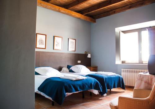 San Pedro del ValleにあるCasa Rural La Torrecilla con PISCINA PRIVADAのベッドルーム1室(青いシーツが備わるベッド2台付)