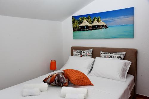 Apartments Martiva في كوتور: غرفة نوم بسرير ذو شراشف بيضاء ولوحة على الحائط