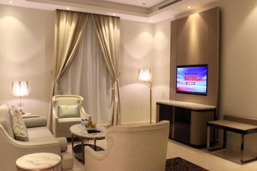 比沙堡的住宿－Malfa Hotel Apartments，客厅配有椅子和墙上的电视