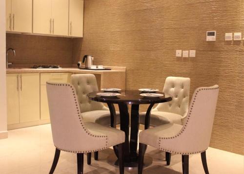 a dining room with a table and white chairs at Malfa Hotel Apartments in Qal'at Bishah