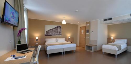 una camera d'albergo con 2 letti e una scrivania con un computer di Nuovo Albergo Operai a Monfalcone