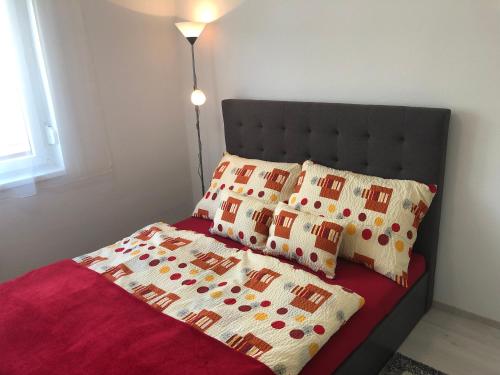 un letto con coperta rossa e cuscini sopra di Szende Apartman a Balatonfüred