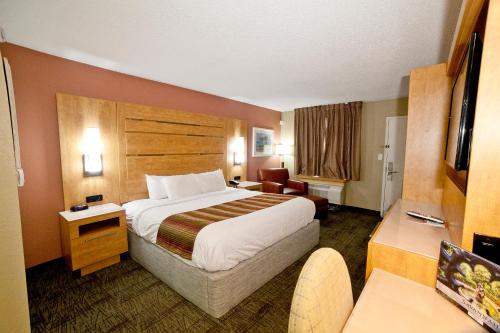 a hotel room with a large bed and a chair at DeSoto Beach Hotel in Tybee Island