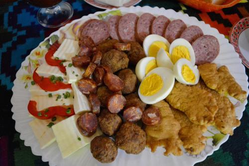 a plate of food with eggs sausage and other foods at Casa Papițu in Vadu Izei