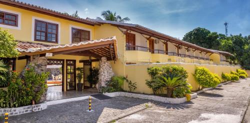 une maison jaune avec une cour en face dans l'établissement Chauã Porto Hotel, à Porto Seguro