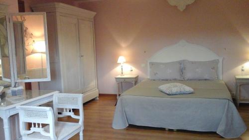 a bedroom with a bed and two white chairs at Chambres d'Hôtes La Rompardais in Pléven