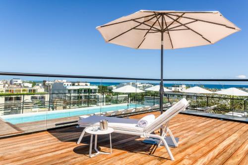 a patio with an umbrella and a chair and a table at Serenity Hotel Boutique By Alsol in Playa del Carmen