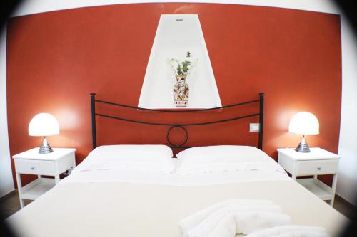 una camera con un letto bianco con una parete rossa di Casa vacanze Anthea a Laterza