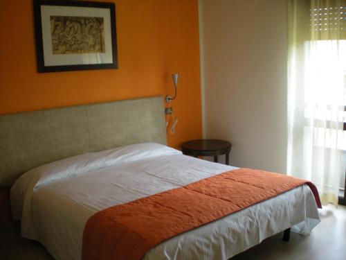a bedroom with a bed with an orange wall at Aer Hotel Malpensa in Oleggio