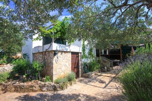 a stone house with a gate in a garden at Apartment Lavender in Selca kod Bogomolja