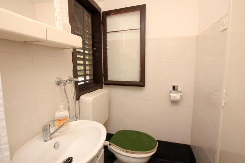 a bathroom with a toilet and a sink and a window at Apartment Lavender in Selca kod Bogomolja