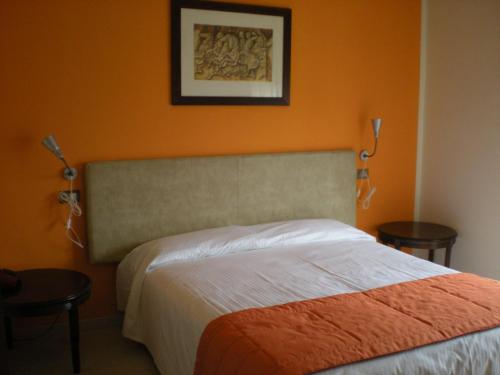 オレッジョにあるエア ホテル マルペンサのベッドルーム1室(オレンジ色の壁のベッド1台付)