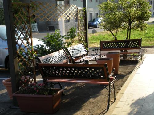 two benches sitting on a sidewalk next to potted plants at Aer Hotel Malpensa in Oleggio