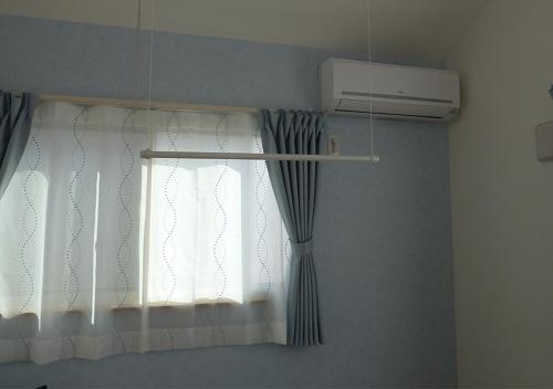 a window with a curtain and a air conditioner at Kanaloa Funabashi in Funabashi