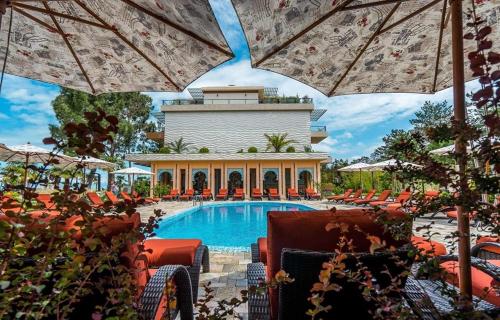 a pool with chairs and umbrellas in front of a resort at Ana's Apartment in Chakvi Oasis in Chakvi