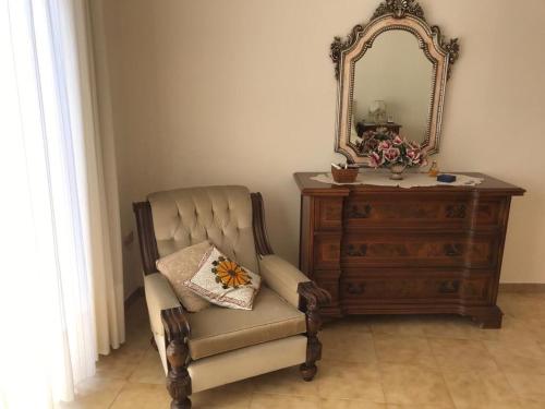 a chair sitting next to a dresser and a mirror at La Gardenia in Ioppolo Giancaxio
