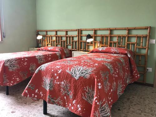 a bedroom with two beds with red comforters at B&B Ospedale Maggiore Parma affittacamere in Parma