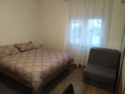 a bedroom with a bed and a chair and a window at Apartments Nediljko & Mila in Zadar