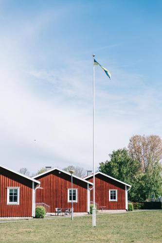 a red building with a flag pole in front of it at Visingsö Vandrarhem in Visingsö
