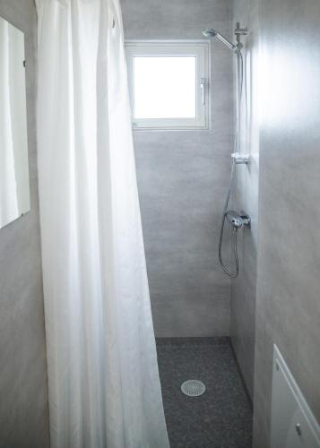 a shower with a white shower curtain in a bathroom at Visingsö Vandrarhem in Visingsö