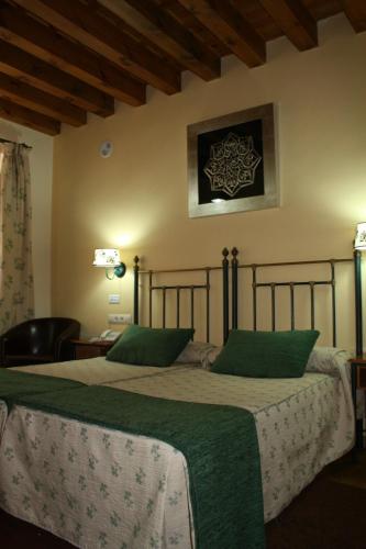 a bedroom with two beds with green pillows at Hotel Spa La Casa Mudéjar in Segovia