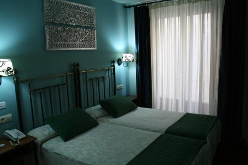 a bedroom with a bed with green walls and a window at Hotel Spa La Casa Mudéjar in Segovia
