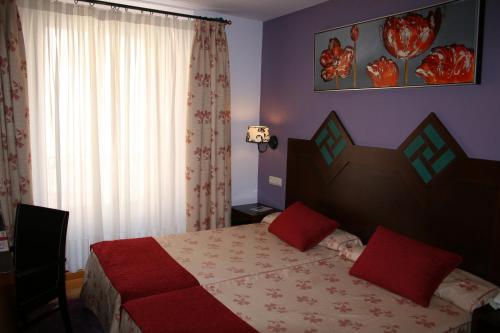 a bedroom with a bed with red pillows on it at Hotel Spa La Casa Mudéjar in Segovia