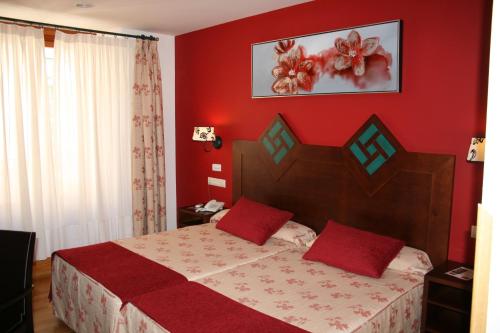 a bedroom with a bed with red walls at Hotel Spa La Casa Mudéjar in Segovia
