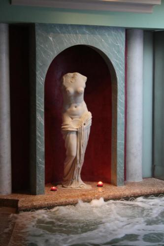 a statue of a woman sitting on a wall next to water at Hotel Spa La Casa Mudéjar in Segovia