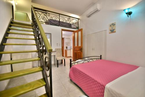 a bedroom with a staircase and a bed with a pink blanket at 2-level Apartment "Mandraki" in Hydra
