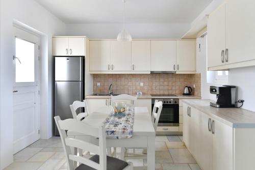 a kitchen with white cabinets and a table and chairs at Villa Dinos in Aliki