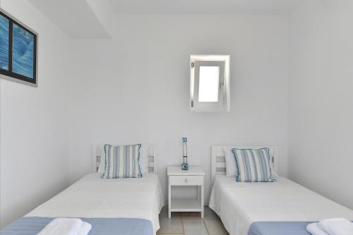 a white room with two beds and a window at Villa Dinos in Aliki