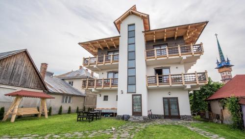a large white house with a courtyard and a church at La Conacul Vesel Săpânța in Săpînţa