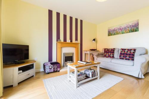 a living room with a couch and a tv at Riverside cottage in Evesham