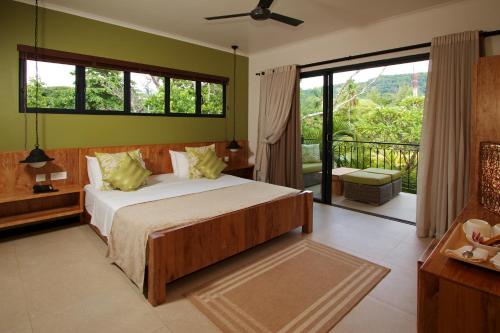 une chambre avec un grand lit et un balcon dans l'établissement Le Repaire - Boutique Hotel & Restaurant, à La Digue