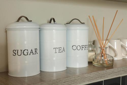 four white coffee cans sitting on a shelf at Patterson B&B in Newcastle