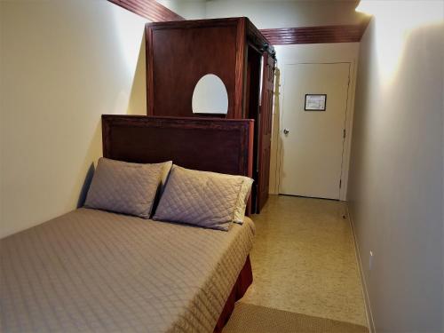 - une chambre avec un lit et une tête de lit en bois dans l'établissement Auberge Internationale La Vieille École, à Sainte-Anne-des-Monts