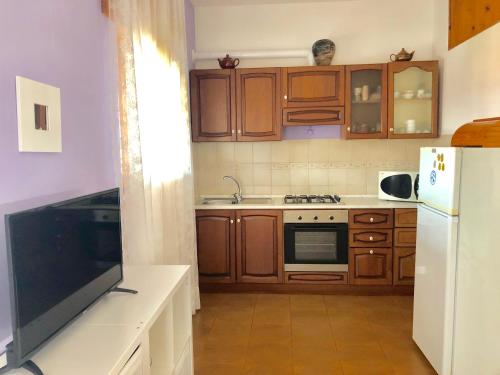 una cucina con armadi in legno e frigorifero bianco di Apartment Arianna 150mt from beach a Castelsardo