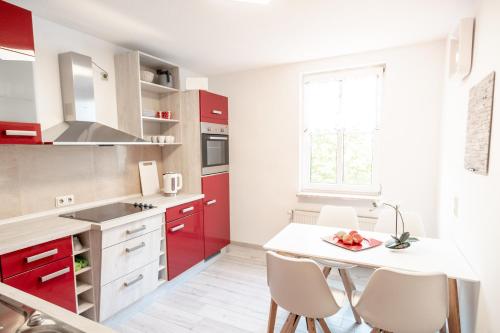 eine Küche mit roten Schränken und einem Tisch mit Stühlen in der Unterkunft Ferienwohnungen am "Spiel-emagazin" in Halberstadt