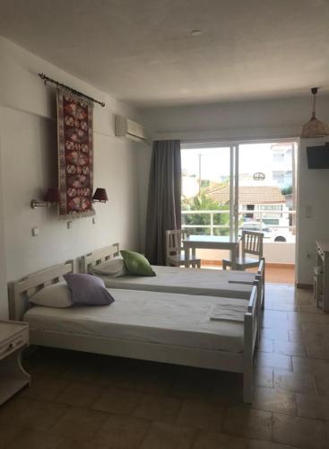 a bedroom with two beds and a large window at Kostas Studios in Faliraki