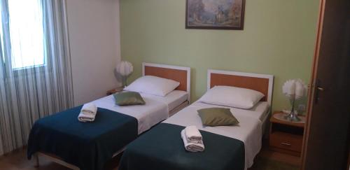 two beds in a hotel room with towels on them at Guest House Ana in Zadar