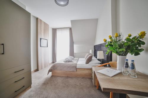 a bedroom with a bed and a table with a vase of flowers at Hotel Kompleks Beskid z basenem i stokiem narciarskim - blisko Babiej Góry in Spytkowice